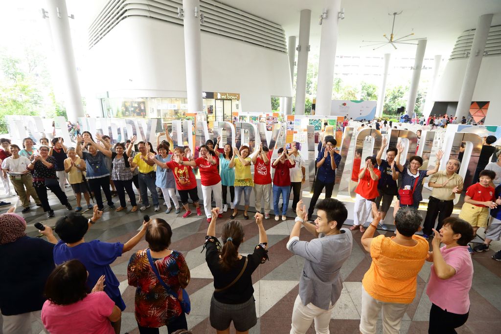 Seniors who participated in ‘It’s A Happy Happy World,’ together with an installation consisting of a hundred quotes from the participants about their reflections on happiness