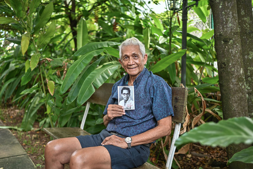 Mr Edmund Rodrigues, holding an old portrait of him in his 20s, outside his house.